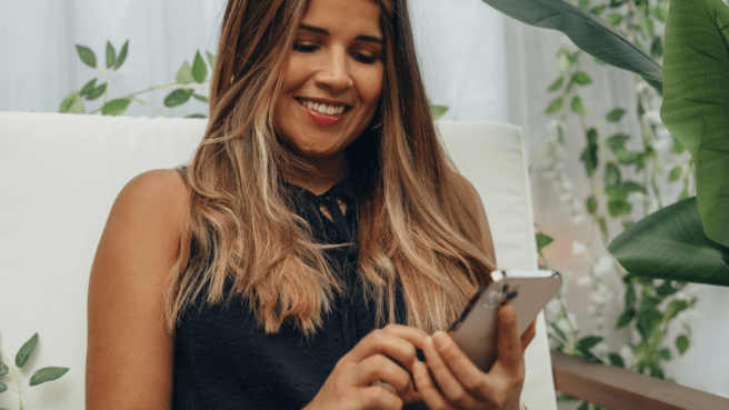 woman on her phone using tiktok and smiling