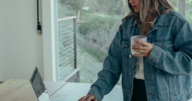 woman reviewing financial statements on the computer holding coffee