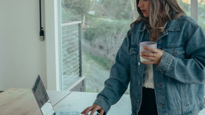 woman reviewing financial statements on the computer holding coffee