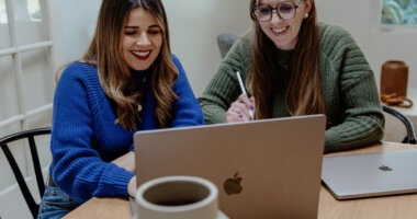 Two women on a marketing team using AI tools on a laptop