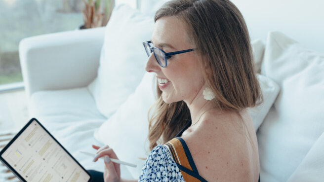 Woman using an tablet in a bright living room smiling