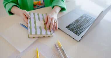 person doing research with laptop and notebooks and pens