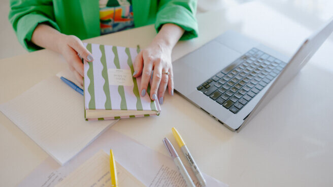 person doing research with laptop and notebooks and pens